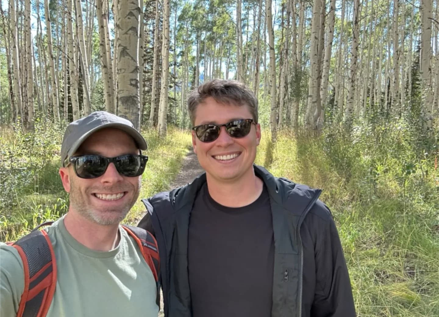 Two Thatch teammates on a hiking trail through an aspen grove